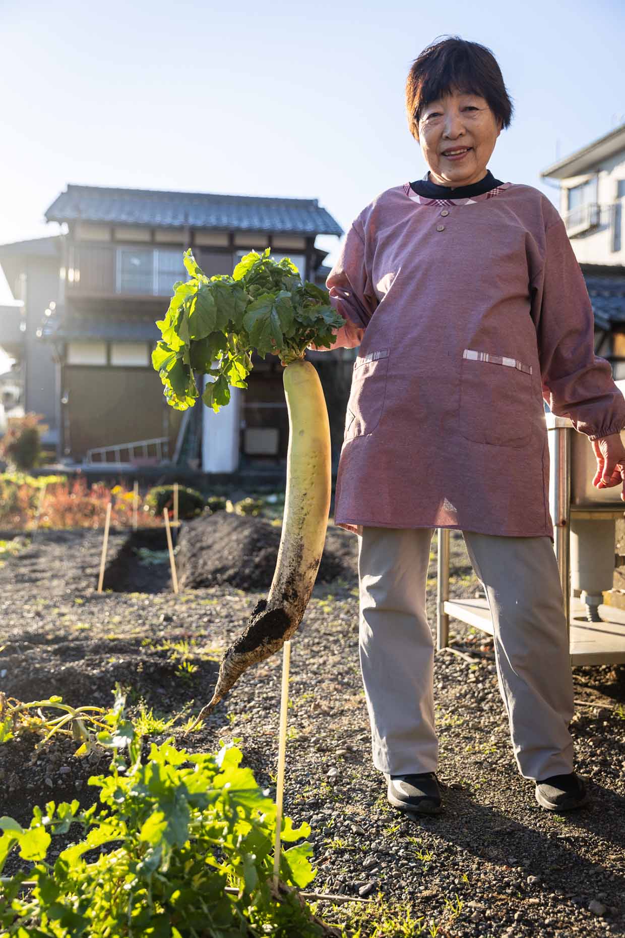 「いわね書店」の岩根ふみ子さんが畑に立つところ