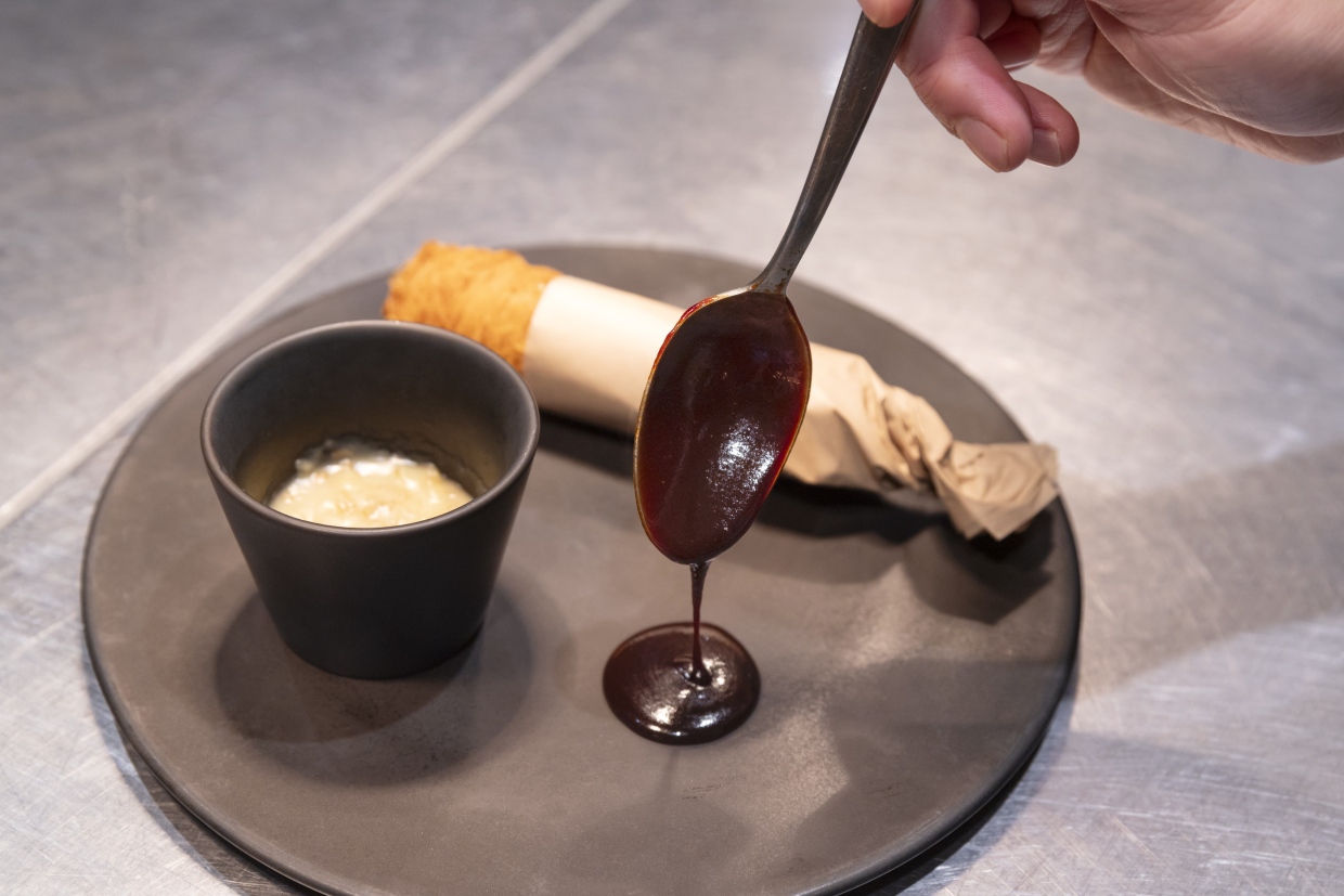 『MAISON VERTE』鴨肉のカダイフ包み焼きに赤ワインソースをかける様子